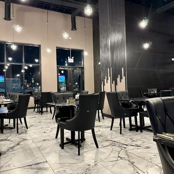 Soulé restaurant interior with black chairs, marble floors, geometric pendant lights, and large windows.