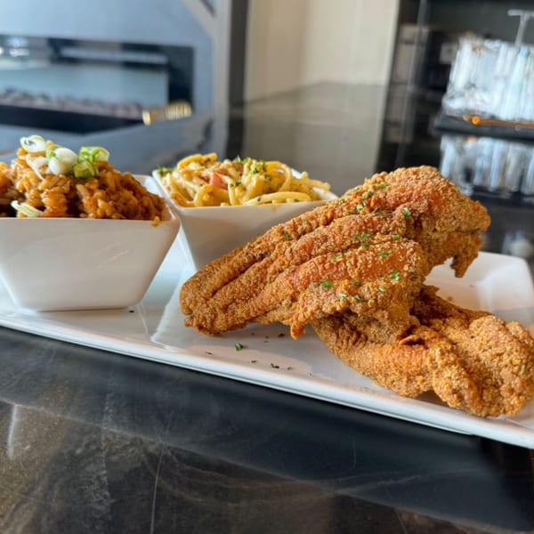 Soulé's fried catfish with sides of jambalaya and macaroni and cheese on a white platter.