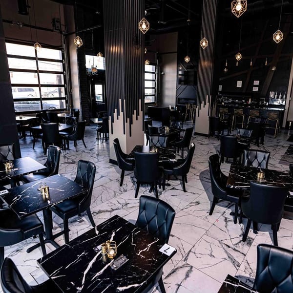 Soulé restaurant interior with black marble tables, black chairs, and geometric pendant lights.