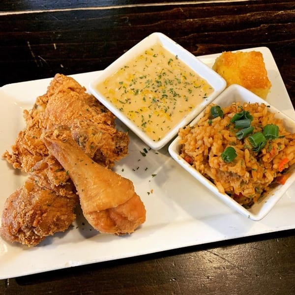 Soulé's fried chicken with sides of mac and cheese, jambalaya, and cornbread on a white plate.