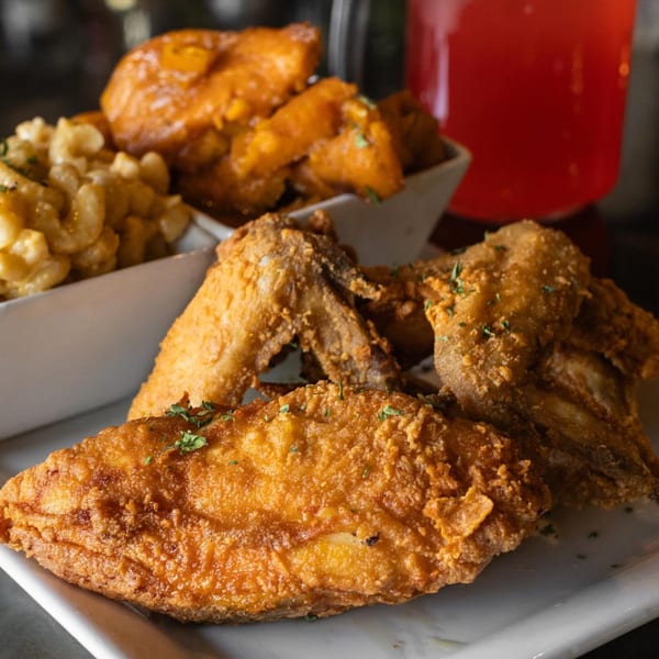 Soulé's fried chicken, mac and cheese, and candied yams with a red drink in the background.