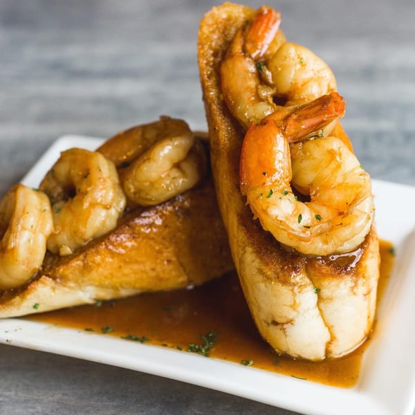 Soulé's shrimp and grits, featuring plump shrimp atop toasted bread, drizzled with a rich sauce.