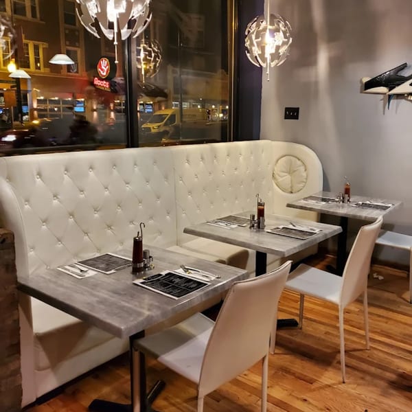 Soulé restaurant interior with white tufted booths, gray tables, and modern light fixtures.