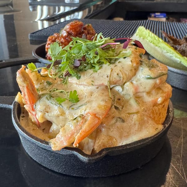 Soulé's creamy shrimp and grits, garnished with fresh herbs, served in a cast iron skillet.
