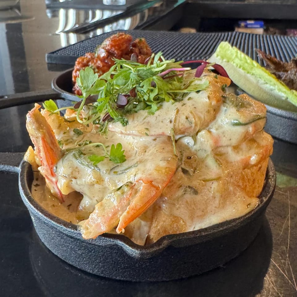 Soulé's creamy shrimp and grits, garnished with fresh herbs, served in a cast iron skillet.